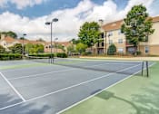 Thumbnail 3 of 19 - Apartments in Duluth, GA 30096 for Rent – Grande Club - A tennis court is surrounded by apartment buildings.