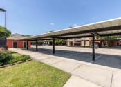 Thumbnail 17 of 20 - Sugar Mill Apartments in Addis, LA photo of a covered parking lot with a building in the background