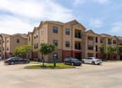 Thumbnail 18 of 20 - Sugar Mill Apartments in Addis, LA photo of a large apartment building with cars parked in front of it