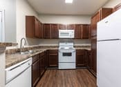 Thumbnail 1 of 20 - Sugar Mill Apartments in Addis, LA photo of a kitchen with white appliances and wooden cabinets