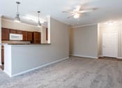 Thumbnail 6 of 20 - Sugar Mill Apartments in Addis, LA photo of an empty living room with a kitchen and a ceiling fan