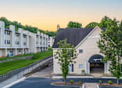 Thumbnail 18 of 21 - Leasing Office entrance at Sugar Creek Apartments with landscaped grounds and nearby apartment homes in Winston-Salem
