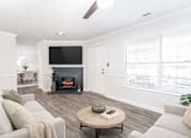 Thumbnail 3 of 21 - Spacious living room with fireplace, wood-style flooring, and natural light at Sugar Creek Apartments in Winston Salem NC