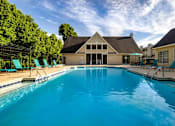 Thumbnail 1 of 21 - Resort style swimming pool and clubhouse at Sugar Creek Apartments in Winston Salem NC with outdoor lounge seating