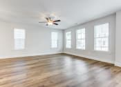 Thumbnail 7 of 25 - an empty living room with hardwood floors and a ceiling fan