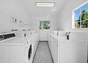 Thumbnail 17 of 21 - On-site laundry room with washers and dryers for residents at Sunnyside Senior Apartments in San Dimas, California