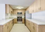 Thumbnail 15 of 29 - Apartments in Santa Monica CA for Rent - San Vicente Tower - Modern Kitchen with Stainless Steel Appliances, White Countertops, and Light Wood-Style Cabinetry
