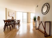 Thumbnail 2 of 29 - Santa Monica, CA Apartments near LAX - San Vicente Tower - Dining Area on Hardwood Flooring with White Walls, Mounted Mirror, Table with Chairs, and Balcony Access