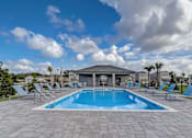 Thumbnail 7 of 36 - A swimming pool surrounded by a stone patio and lounge chairs.