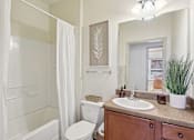 Thumbnail 13 of 32 - Modern bathroom featuring wood cabinetry and updated fixtures at Tattersall Village Apartments near Fort Stewart