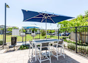 Thumbnail 40 of 55 - A table with chairs and an umbrella is set up on a patio.