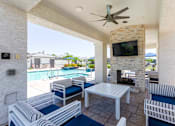 Thumbnail 42 of 55 - A patio with a white couch, blue cushions, and a television above a fireplace.