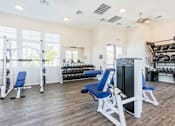 Thumbnail 29 of 55 - A gym with a variety of equipment including a leg press machine, a squat rack, and a bench press.