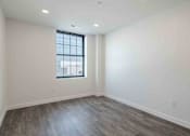 Thumbnail 26 of 27 - an empty living room with white walls and a window