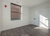 Thumbnail 18 of 27 - a bedroom with white walls and a window and a door