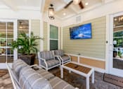 Thumbnail 15 of 32 - A patio with a couch, chair, and a television on the wall.