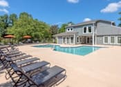 Thumbnail 19 of 25 - Apartment complex swimming pool with lounge chairs and umbrellas.
