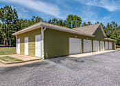 Thumbnail 21 of 24 - a row of garages in front of a grassy area with trees in the background