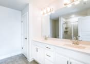 Thumbnail 12 of 16 - a bathroom with white cabinets and a large mirror