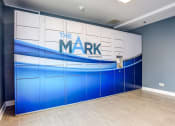 Thumbnail 9 of 11 - Glendale Heights Apartments - package locker storage room with blue and white painted doors and a large property logo for The Mark