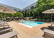 Thumbnail 23 of 39 - A large outdoor pool area with sun loungers and umbrellas.
