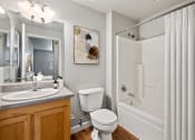 Thumbnail 10 of 19 - Pet-Friendly Apartments In Petaluma, CA - Bathroom With Wood-Plank Flooring, Toilet, Vanity Mirror, Light Wood-Style Cabinetry, And Shower And Tub Combo.