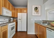 Thumbnail 1 of 19 - 2 Bedroom Apartments in Petaluma, CA - Theatre Square - Kitchen With Light Wood-Style Cabinetry, Breakfast Bar, Granite Countertops, White Appliances, And Wood-Plank Flooring