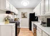 Thumbnail 4 of 16 - Affinitee at Stone Mountain Apartments photo of an open kitchen with white cabinets and a black refrigerator