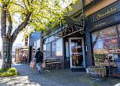 Thumbnail 13 of 15 - a person walking down a sidewalk in front of a store