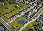 Thumbnail 47 of 47 - A bird's eye view of a residential neighborhood with houses, roads, and a pond.
