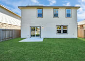 Thumbnail 9 of 41 - 4 Bedroom Single Family Homes for Rent in Houston TX - Imperial Forest - Back of a Home Exterior, with White Walls, Windows, Sliding Glass Back Door, and Grassy Lawns in a Fenced-In Yard