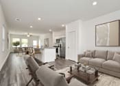 Thumbnail 23 of 41 - A modern living room with a grey sofa, wooden chairs, and a coffee table.