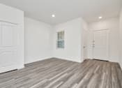 Thumbnail 26 of 41 - A room with white walls and wooden flooring with two doors.