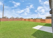 Thumbnail 5 of 39 - Two-BR Homes for Rent in Katy, TX - Villas at Sunterra - Backyard with Well-Maintained Green Grass and a Wooden/Brick Fence
