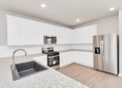 Thumbnail 23 of 39 - Three-BR Homes for Rent in Katy, TX - Villas at Sunterra - Kitchen with White Cabinets, Stainless Steel Appliances, Granite Countertops, and Wood-Style Flooring