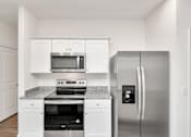 Thumbnail 17 of 41 - A kitchen with a stainless steel refrigerator and a microwave above the stove.