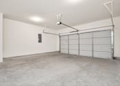 Thumbnail 38 of 41 - A large empty garage with a white door and a grey floor.