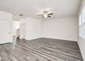 Thumbnail 28 of 41 - Five Bedroom Single Family Homes for Rent in Houston TX - Imperial Forest - Unfurnished Living Room Space with Wood-Style Flooring, White Walls, a Ceiling Fan, Closet Doors, a Window, and View of the 