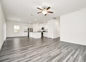 Thumbnail 21 of 41 - A spacious room with a ceiling fan and wooden flooring.
