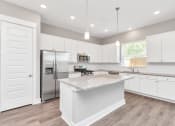 Thumbnail 25 of 34 - a kitchen with white cabinets and a large island with granite countertops