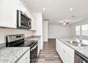 Thumbnail 16 of 41 - Pet-Friendly Homes for Rent in Houston TX - Imperial Forest - Modern Kitchen with White Cabinetry, Stainless Steel Appliances, GRanite Countertops, Dual Silver Sink, and Wood-Style Flooring