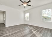 Thumbnail 29 of 41 - A room with a ceiling fan and wooden flooring.