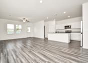 Thumbnail 22 of 41 - A spacious kitchen and living room with wood flooring and white walls.