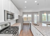 Thumbnail 26 of 34 - a kitchen with white cabinets and granite countertops