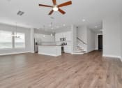 Thumbnail 12 of 34 - Dog-Friendly homes for rent in Heights, Houston TX - The Crossing at Timbergrove - Open-Concept, Empty Living Space with Hanging Lights, a Ceiling Fan, Windows, Hardwood-Inspired Flooring, and a View 