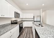 Thumbnail 18 of 41 - A kitchen with granite countertops and white cabinets.