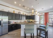 Thumbnail 9 of 21 - a kitchen with black cabinets and a bar with two stools