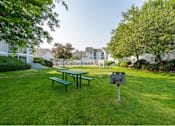 Thumbnail 15 of 17 - a park with a picnic table and a grill in the grass