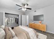 Thumbnail 8 of 12 - Pet-Friendly Apartments in Overland Park– Treetop Lodge – A bedroom with a bed, a TV, and a wardrobe.