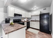 Thumbnail 1 of 12 - Overland Park, KS Apartments – Treetop Lodge – A kitchen with black appliances and white cabinets.